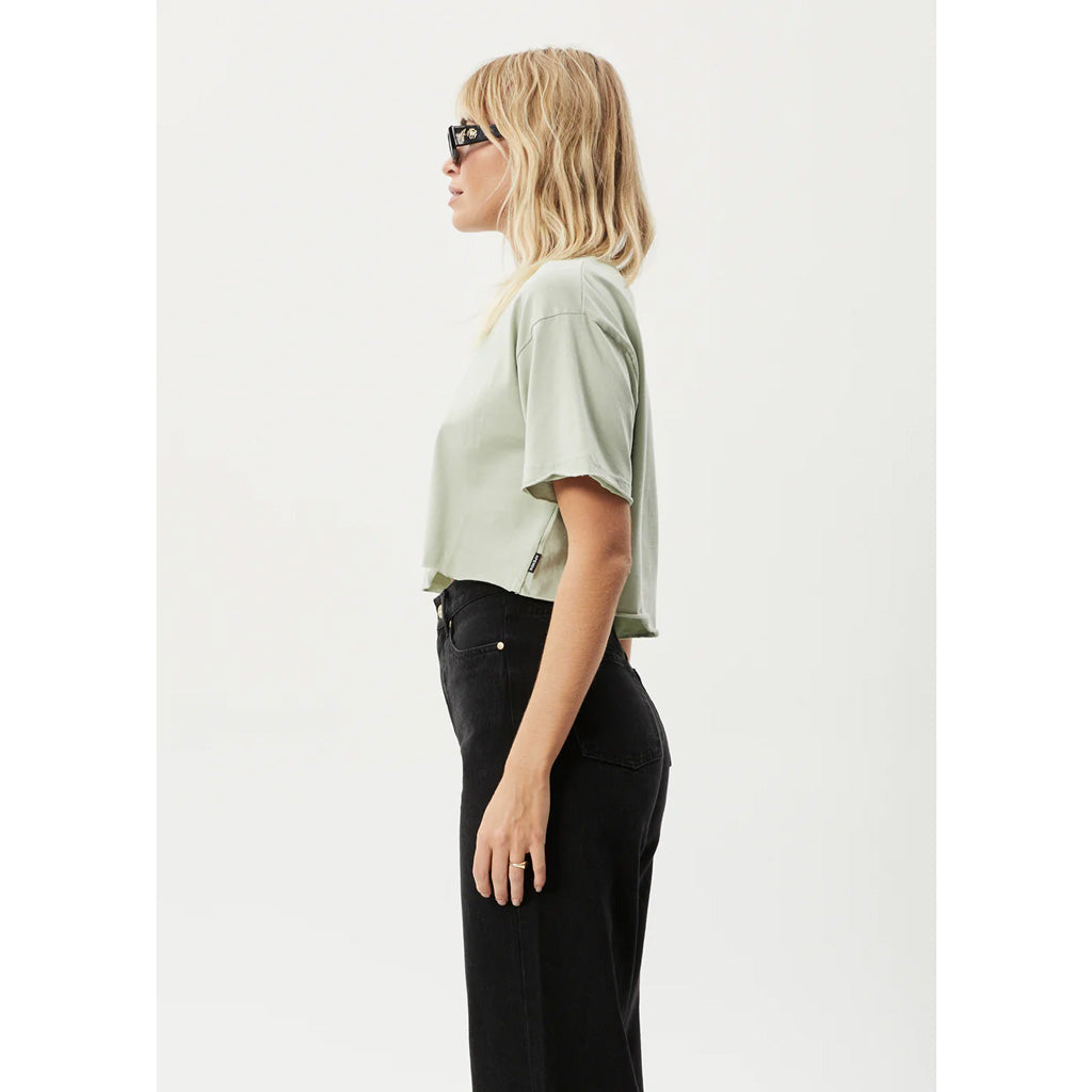 Afends Restless Slay Cropped Recycled Tee - Eucalyptus Womens Basic Cropped T-ShirtBaggy Relaxed FitWide Ribbed NecklineCropped Design Model wears a size S / AU 8 / US 4 and is 178cm tall. 50% Recycled Cotton 50% Organic Cotton JerseyMidweight, 200gsm