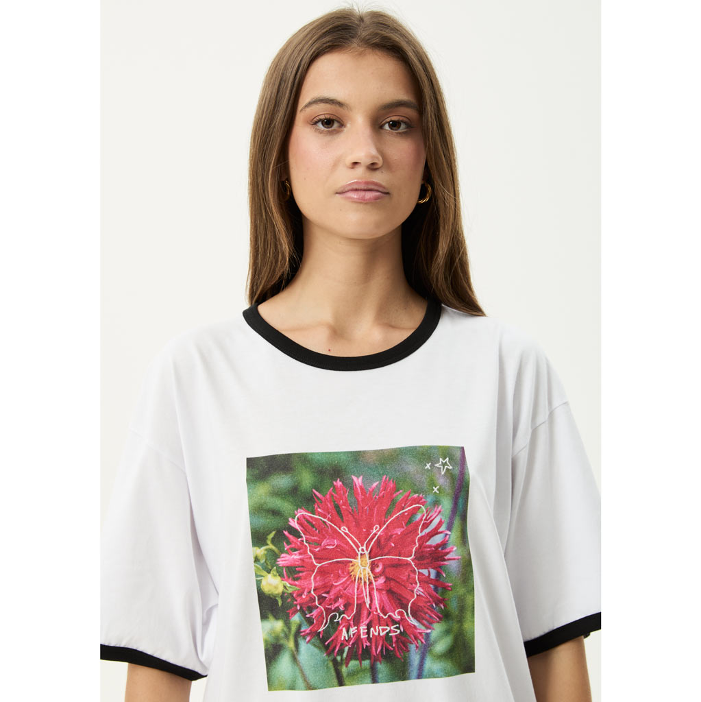 Person wearing a white t-shirt with a colorful butterfly graphic and text on a plain background