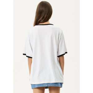 Woman wearing a white oversized t-shirt with black trim on a light gray background